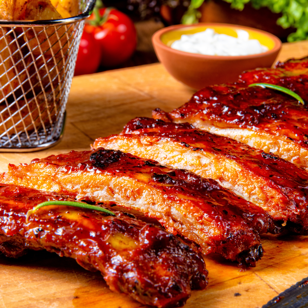 Perfectly cooked bbq ribs sliced on a cutting board getting ready to serve.